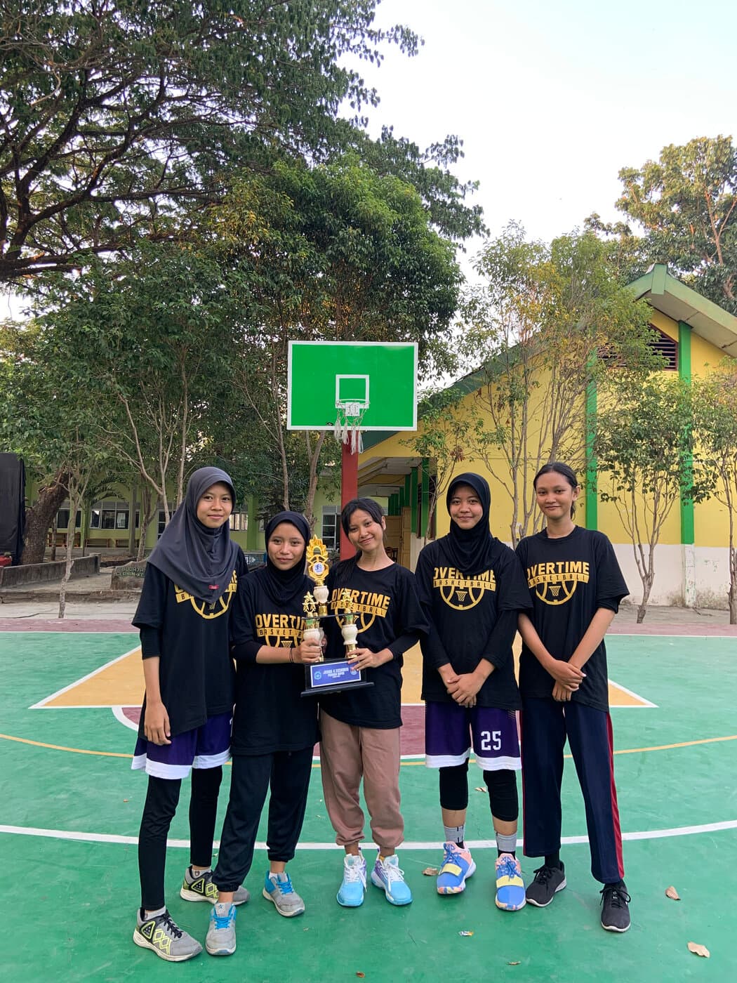 Pemain Overtime Academy membawa piala kejuaraan